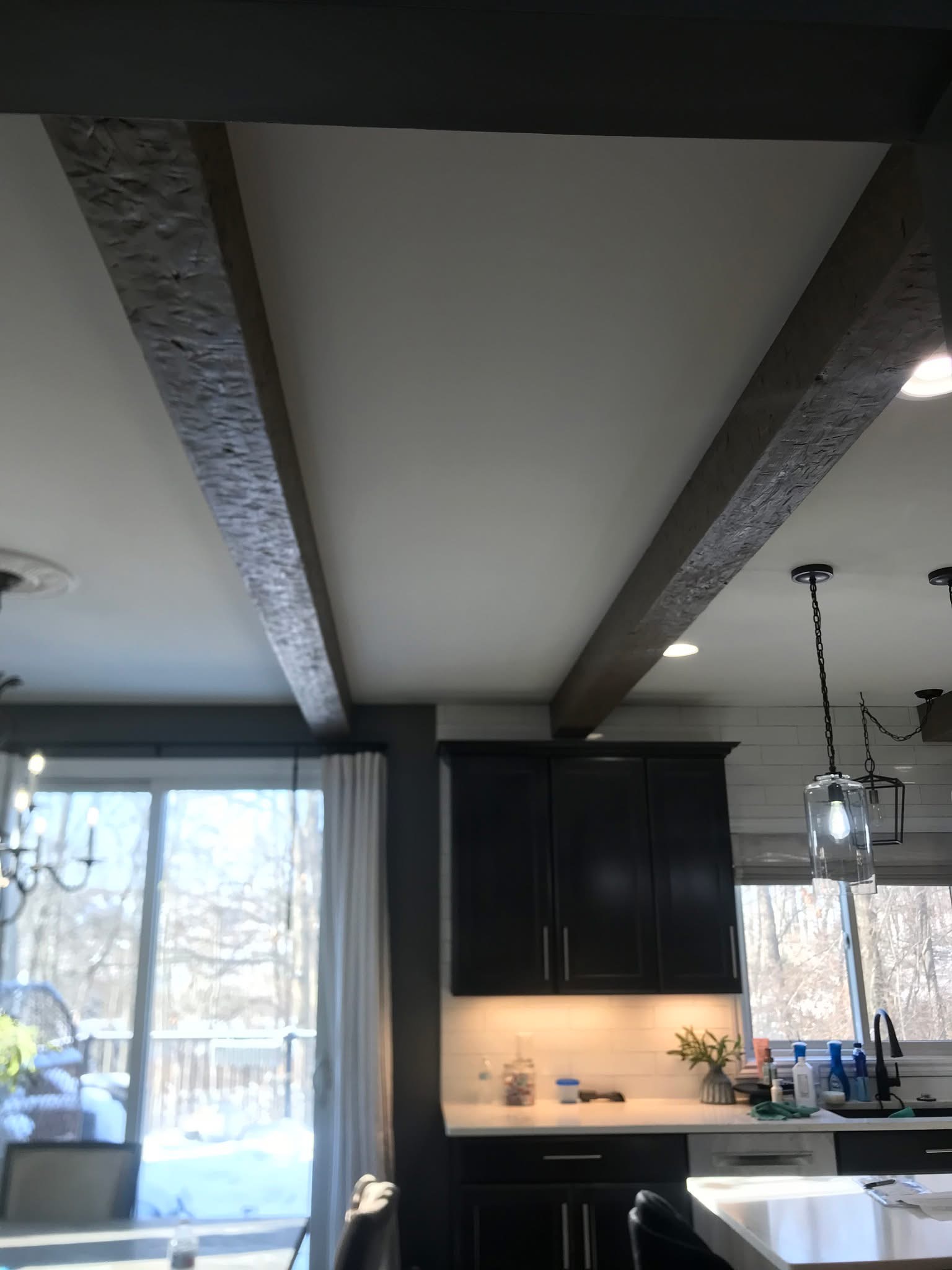 Kitchen remodel with exposed wood ceiling beams and dark cabinetry